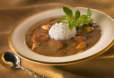 Chicken and Sausage Gumbo with Steamed Rice. Our Gumbo is made from a thick, rich roux that blends a mélange of fresh herbs and spices.  Onions, bell peppers, and celery are slowly sautéed until tender and sweet.  Thick and hearty pieces of chicken and andouille sausage fill every bowl of this delicious Louisiana delicacy.