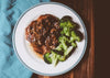 Smothered Pork-Chops. Two large tender slow baked bone-in pork chops smothered in country mushroom gravy served with steamed broccoli. You will love this low calorie, low carb dish. Low carb, Paleo, keto friendly.